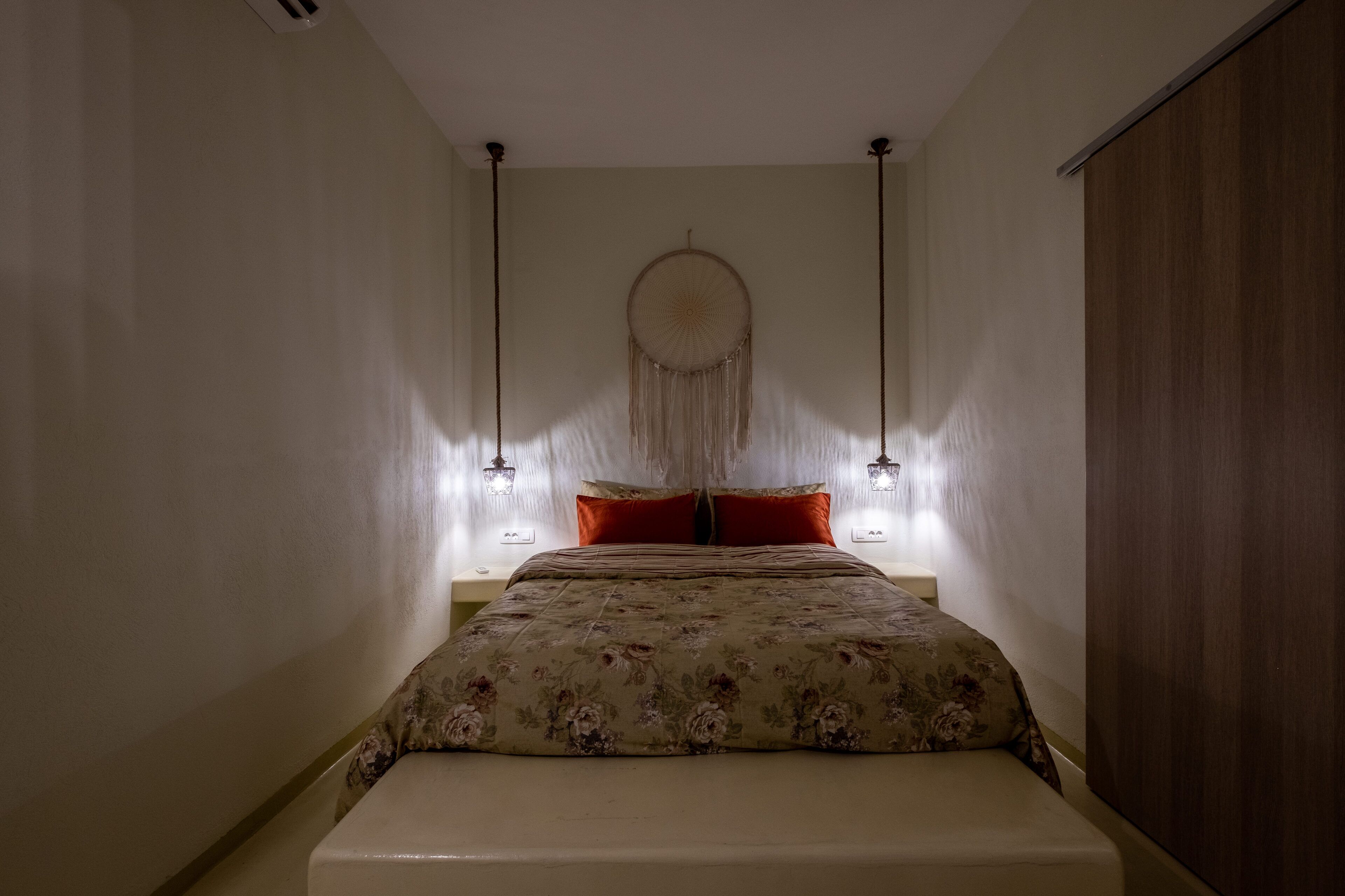 Una camera da letto con un letto, un'acchiappasogni e due lampade a parete.