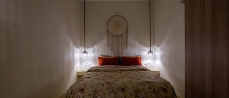 Una camera da letto con un letto, un'acchiappasogni e due lampade a parete.