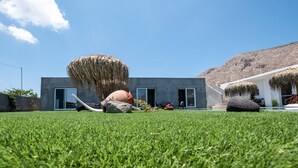 A modern building with a flat roof, large windows, and a well-maintained lawn. - Sagma Villas (Santorini)