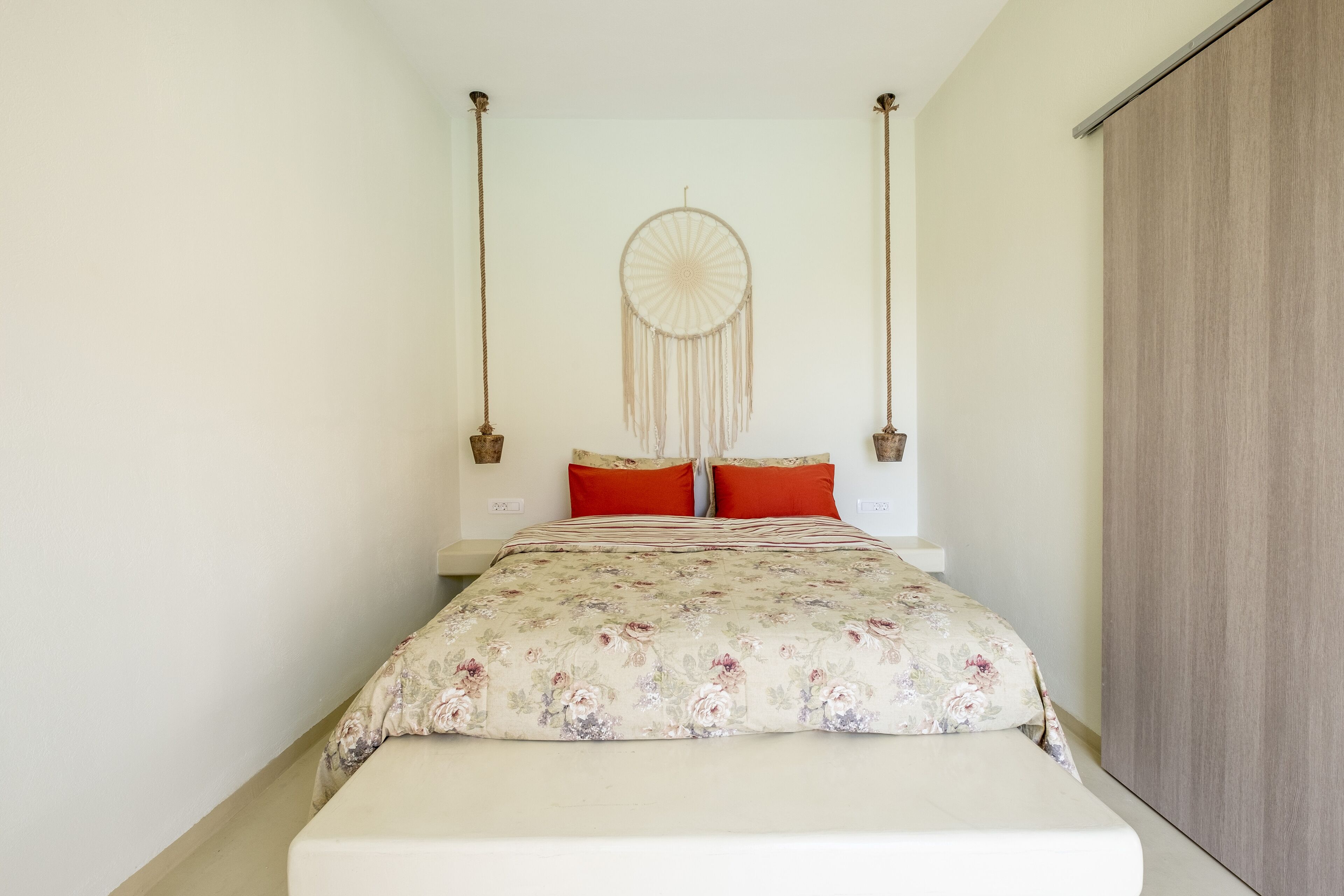 A bedroom with a bed, a dreamcatcher, and a wardrobe.