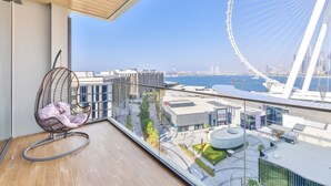 Ein Balkon mit einer Hängematte, Blick auf ein Riesenrad und moderne Gebäude.