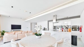 Ein modernes Wohnzimmer mit einem runden Marmortisch, weißen Sofas und einem Fernseher.