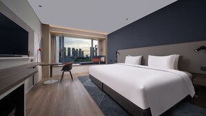 A modern hotel room with a large bed, a desk, and a view of the city skyline. - Holiday Inn Express Shenzhen Guangming Cloud Park by IHG (Shenzhen)