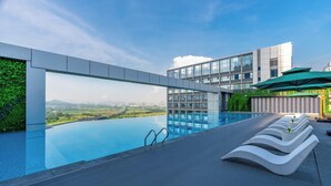 A rooftop infinity pool with a view of a cityscape, modern architecture, and lounge chairs. - Holiday Inn Express Shenzhen Guangming Cloud Park by IHG (Shenzhen)