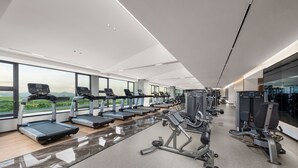 A modern gym with treadmills, weight machines, and a large window offering a view of the mountains. - Holiday Inn Express Shenzhen Guangming Cloud Park by IHG (Shenzhen)