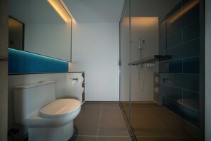A modern bathroom with a toilet, shower, and a glass-enclosed shower area.