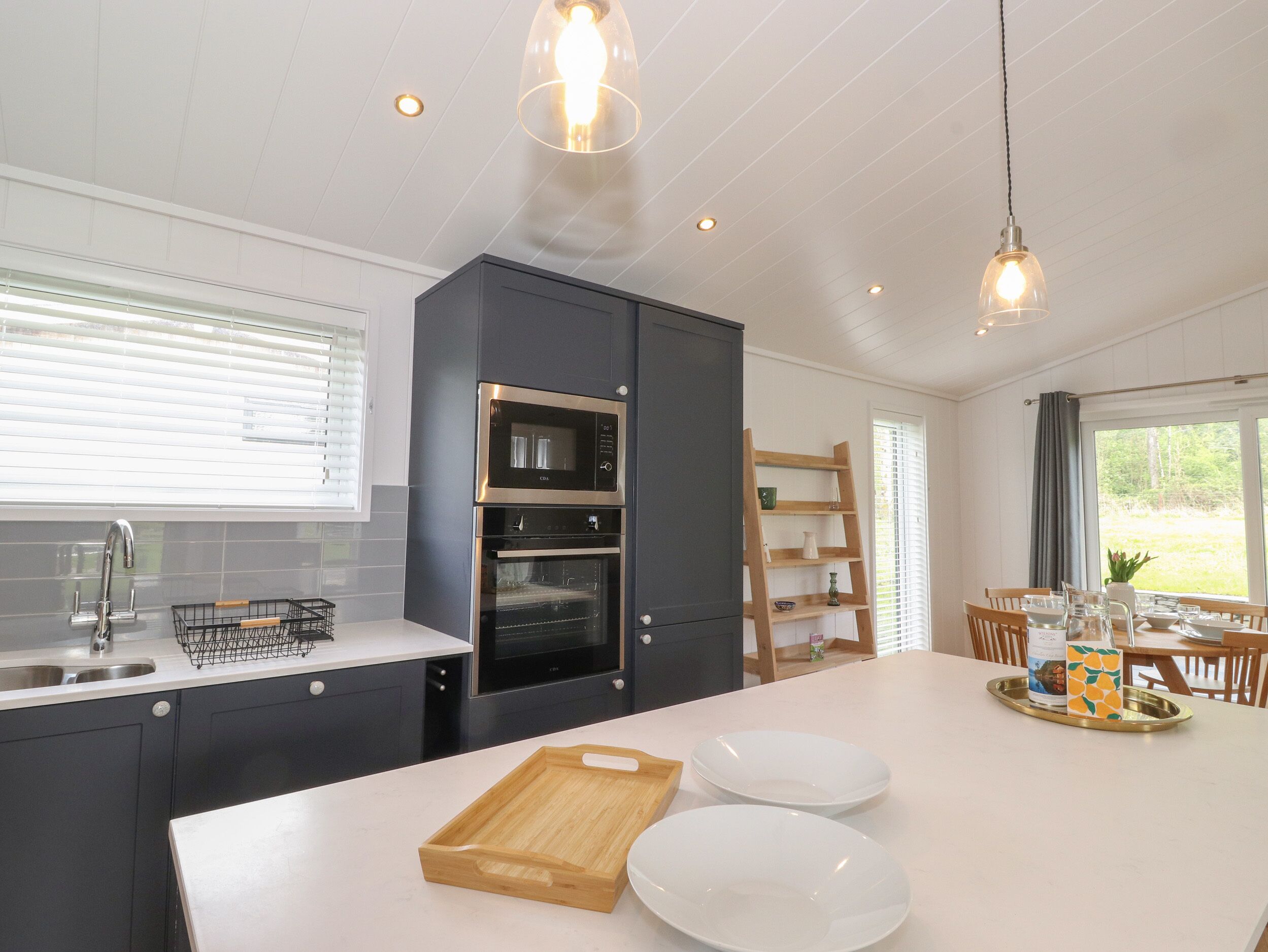 Una cocina moderna con una isla central, horno empotrado y un comedor con vistas.