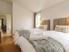 Una habitación de hotel con una cama grande, dos almohadas, una colcha y una ventana con cortinas.
