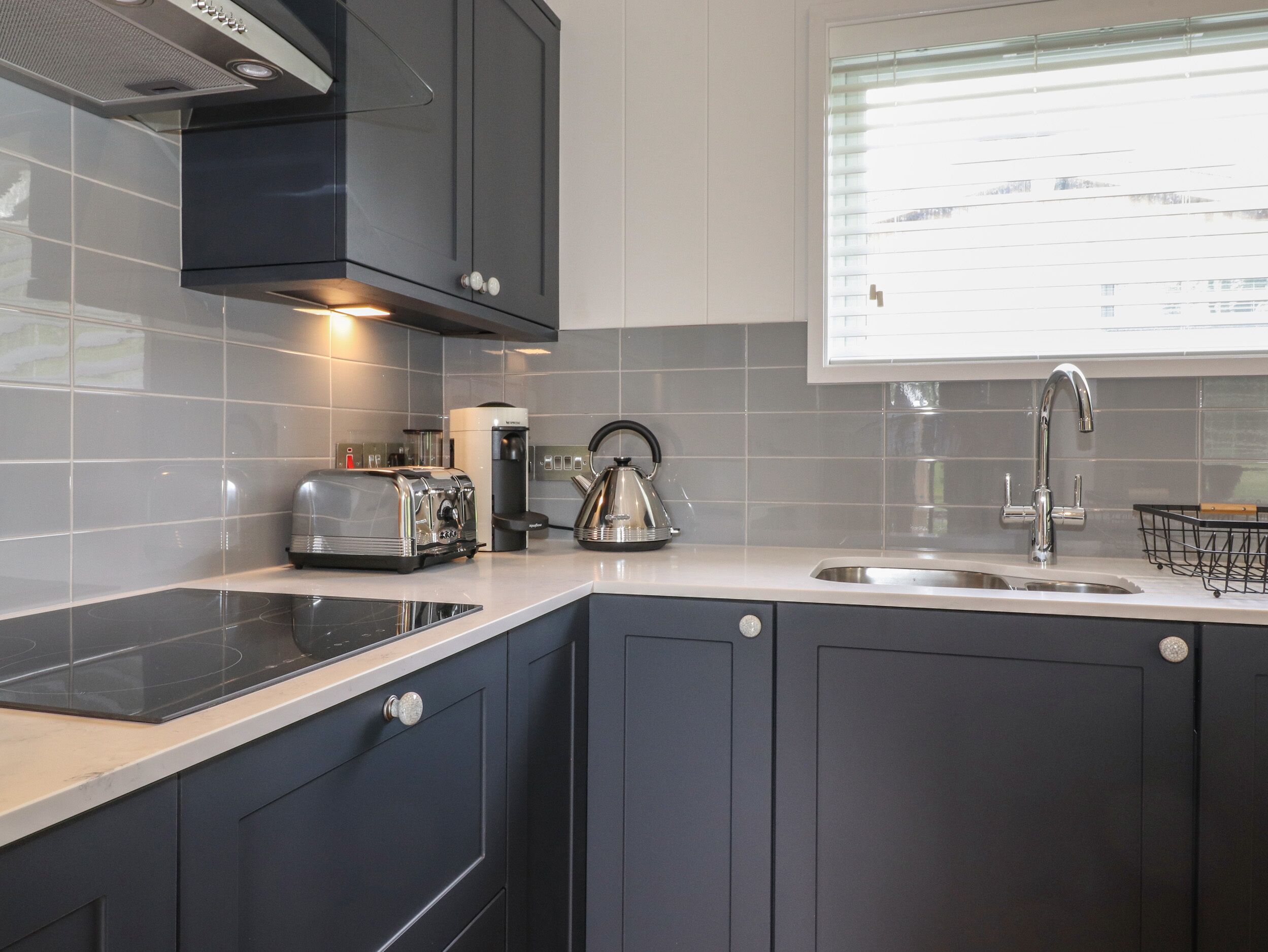Una cucina moderna con mobili scuri, un lavello in acciaio inossidabile, un bollitore e una macchina per il caffè.