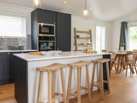 Una cocina moderna con armarios oscuros, electrodomésticos de acero inoxidable y taburetes de madera.