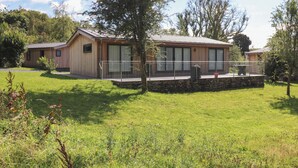 A modern wooden cabin with a stone foundation, large windows, and a covered outdoor area. - Hawthorn Croft (Ulverston)