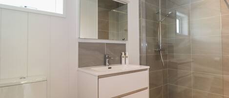 A modern bathroom with a glass shower enclosure, a white vanity with a mirror, and a toilet.