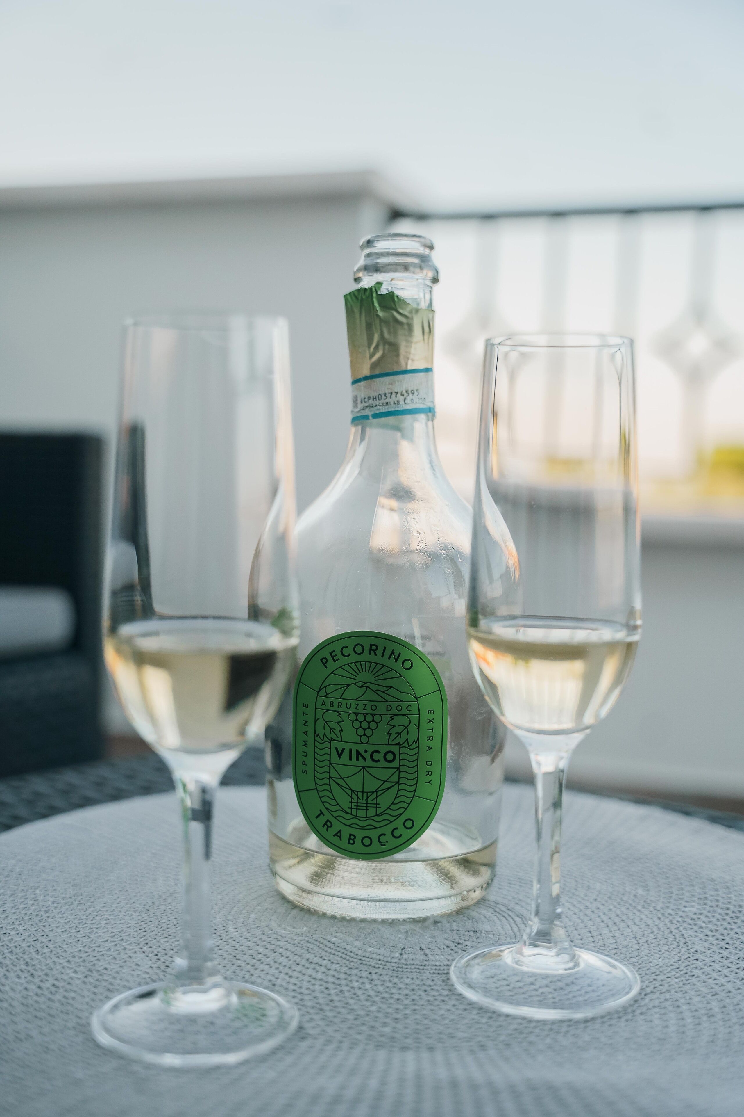 Una botella de vino Pécorining y dos copas sobre una mesa con vistas al cielo.
