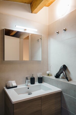 A modern bathroom with a large mirror, a white sink, and a hairdryer on the counter. - B&B TANA DEL RICCIO (Ortona)