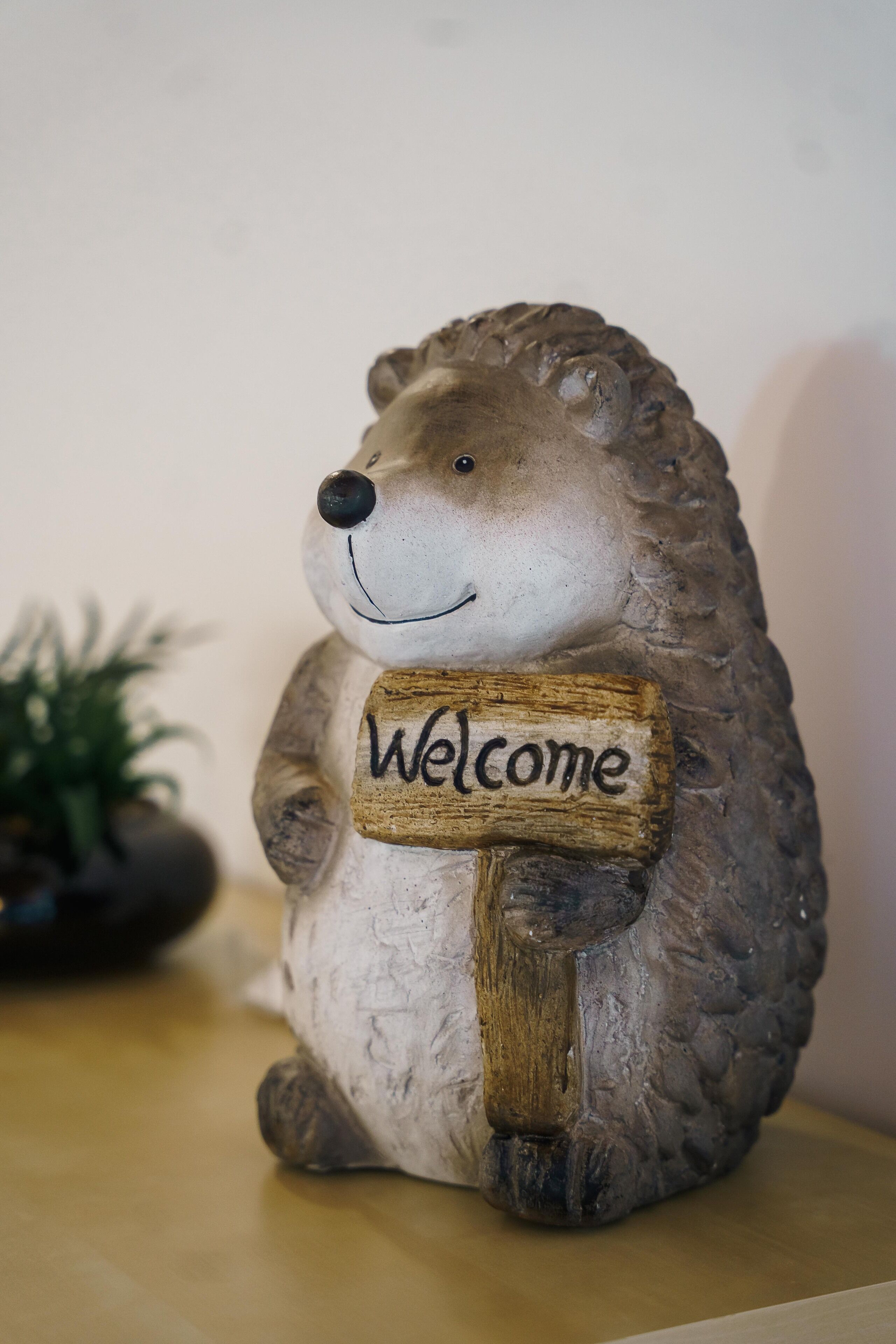 A hedgehog figurine holding a sign that says "Welcome".