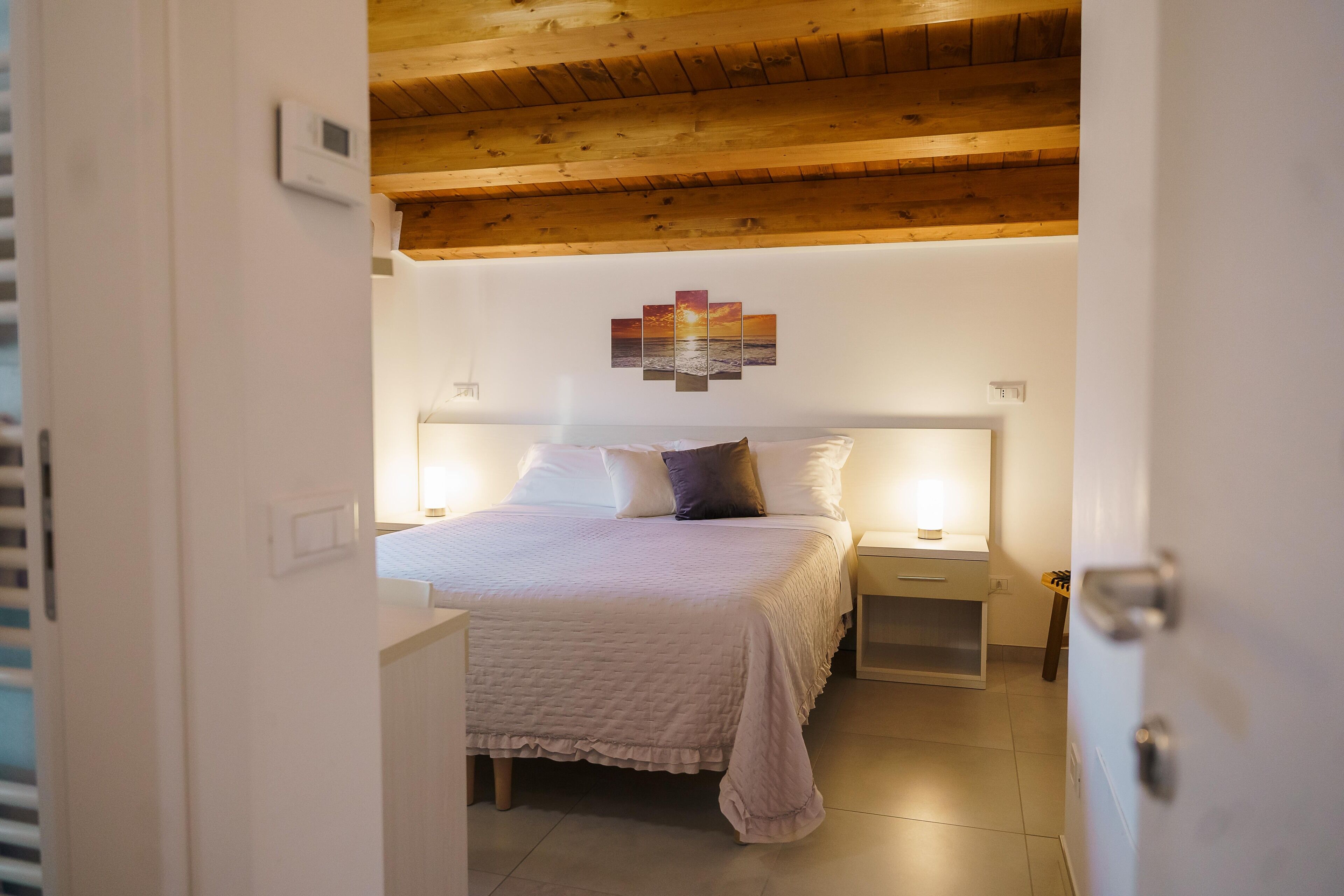 Un dormitorio con cama, mesitas de noche y una obra de arte en la pared.