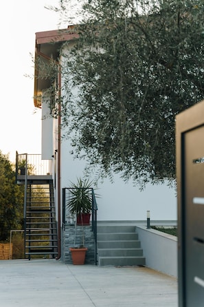 Stylish entrance with a concrete staircase, metal gate, and lush greenery.