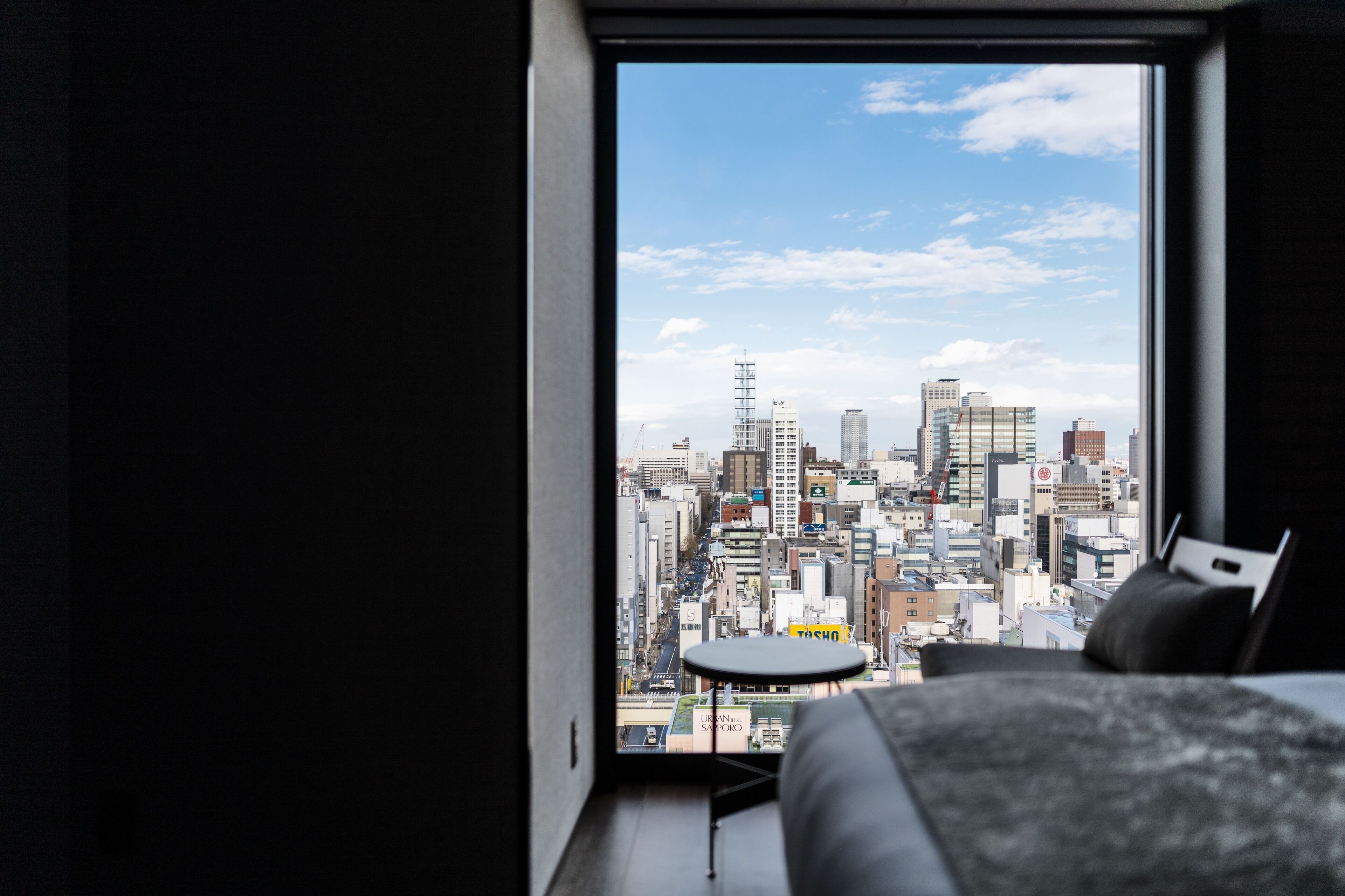 A bedroom with a large window overlooking a cityscape.