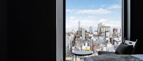 A bedroom with a large window overlooking a cityscape.