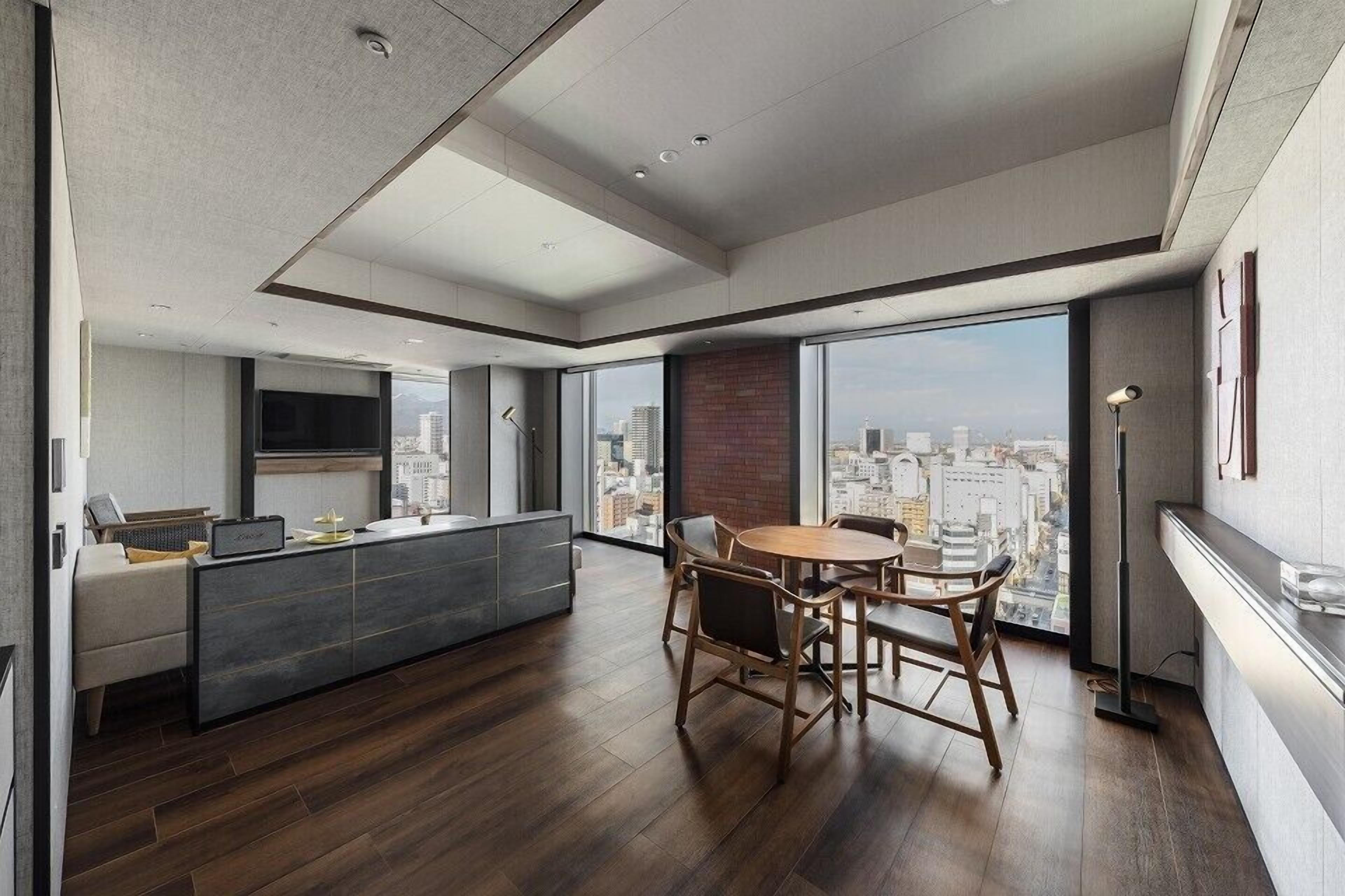 A modern living room with a dining area, large windows, and a city view.