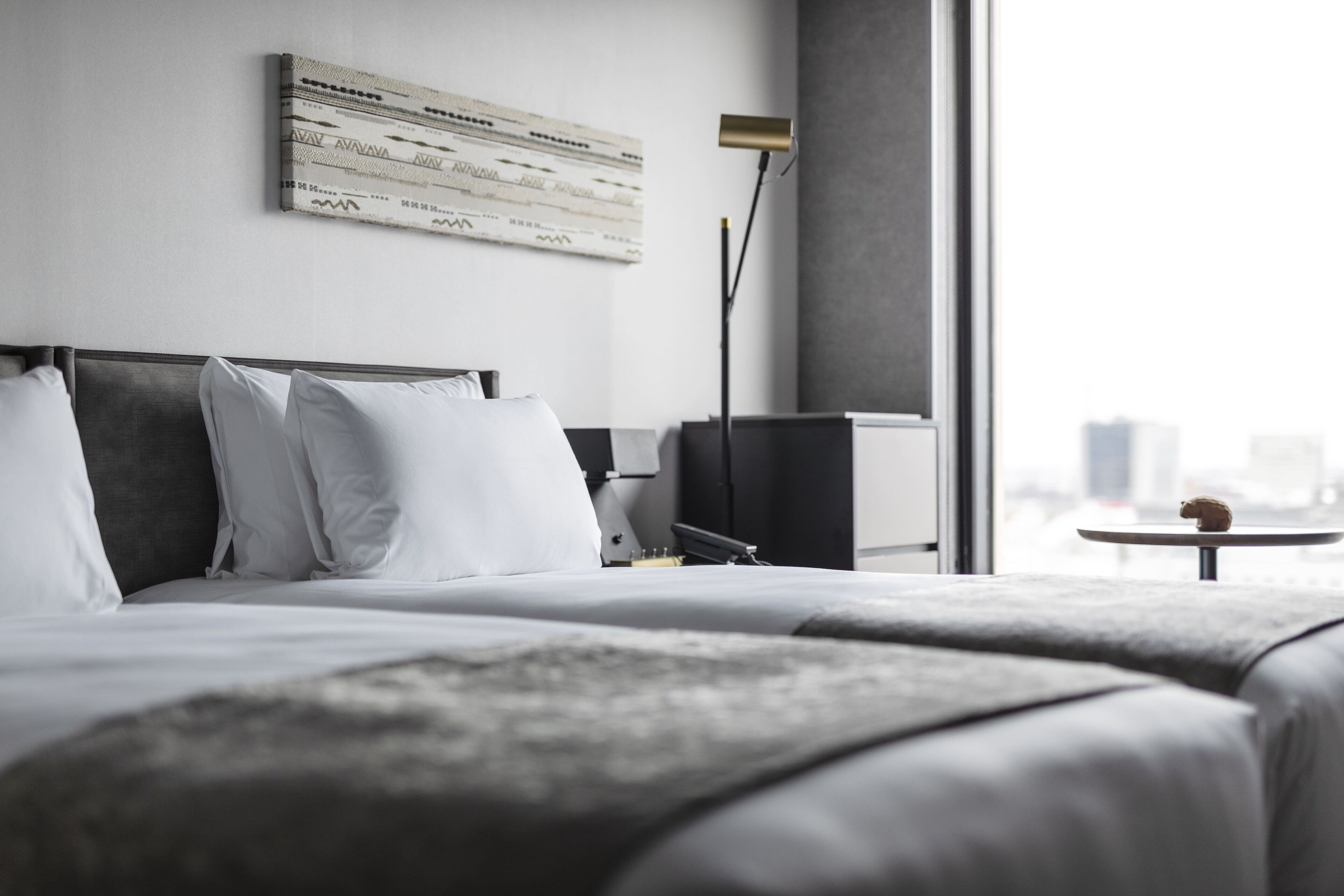 A modern hotel room with a large bed, a flat-screen TV, and a city view.