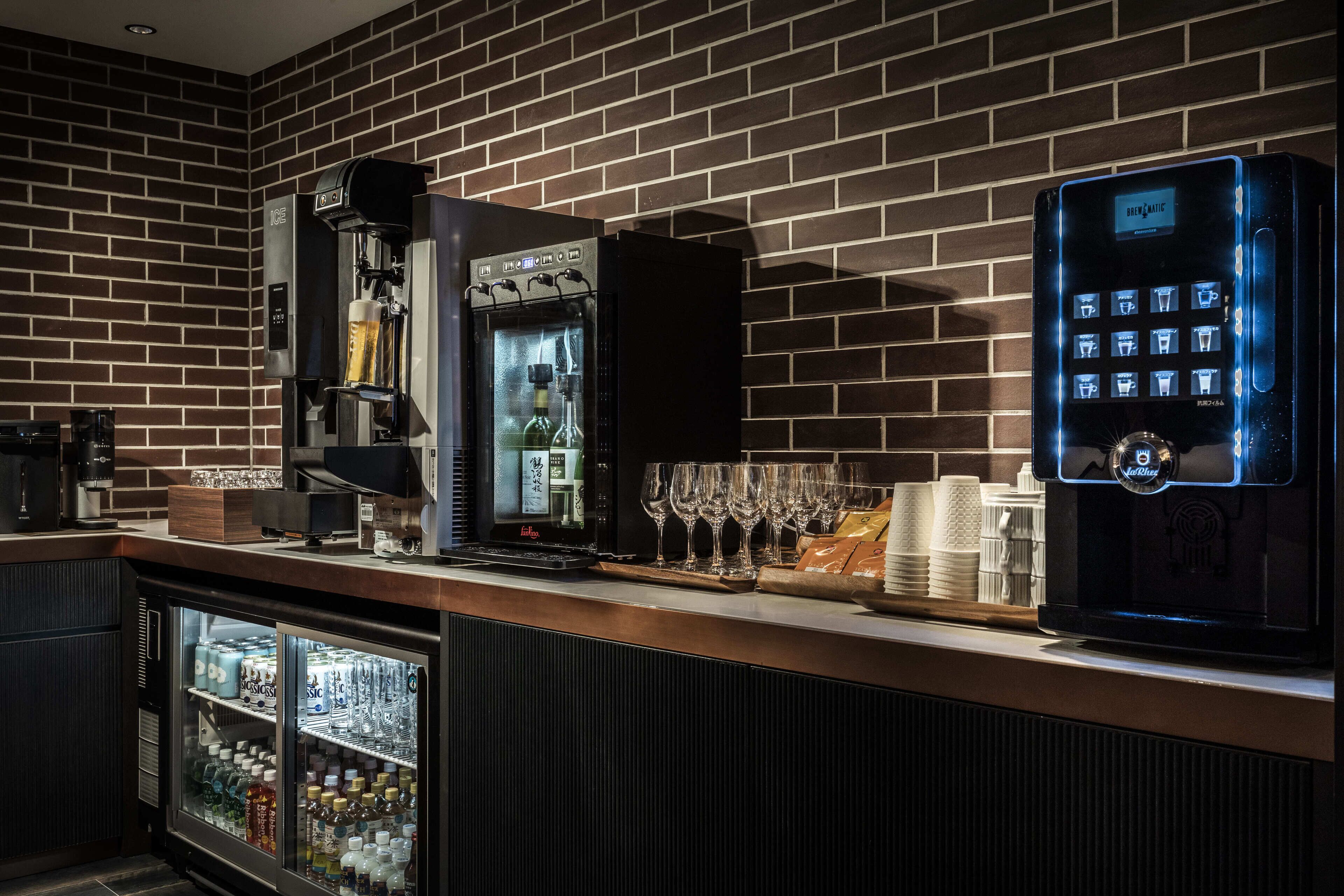 Eine Bar mit einem Kühlschrank, einer Kaffeemaschine und einem digitalen Getränkeautomaten.