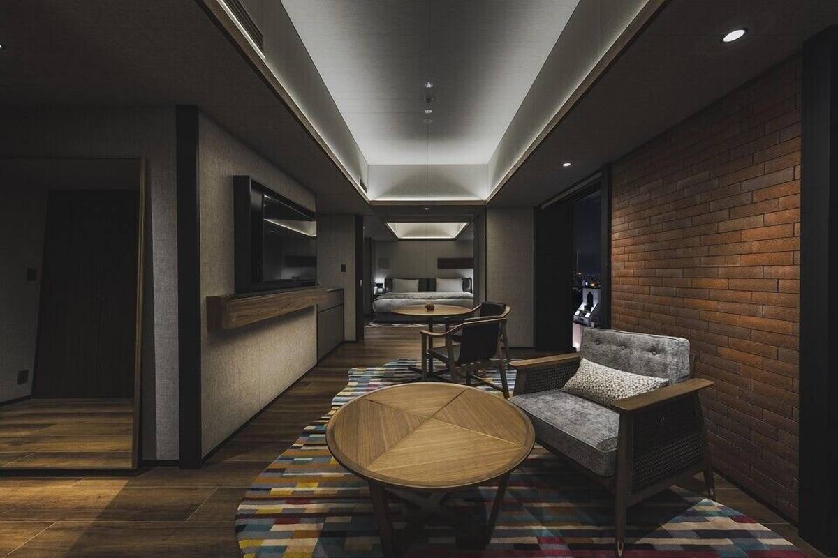 A modern hotel room with a cozy seating area, a dining table, and a kitchen area.
