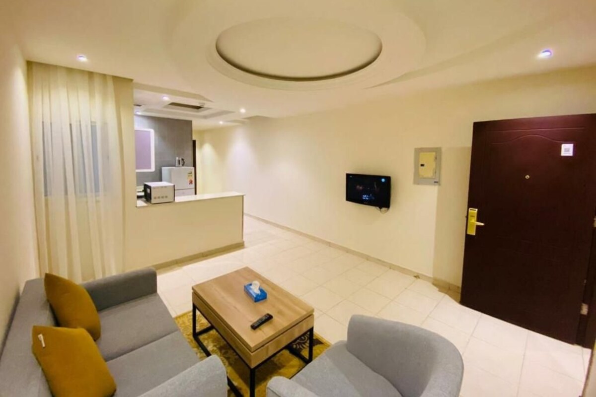 Una camera d'albergo moderna con divano, poltrona e un tavolino con un telecomando.