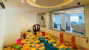 A brightly colored playroom with a star-shaped ceiling design and a large window offering a view of the outside. - Towlan Khress Serviced Apartments (Riyadh)