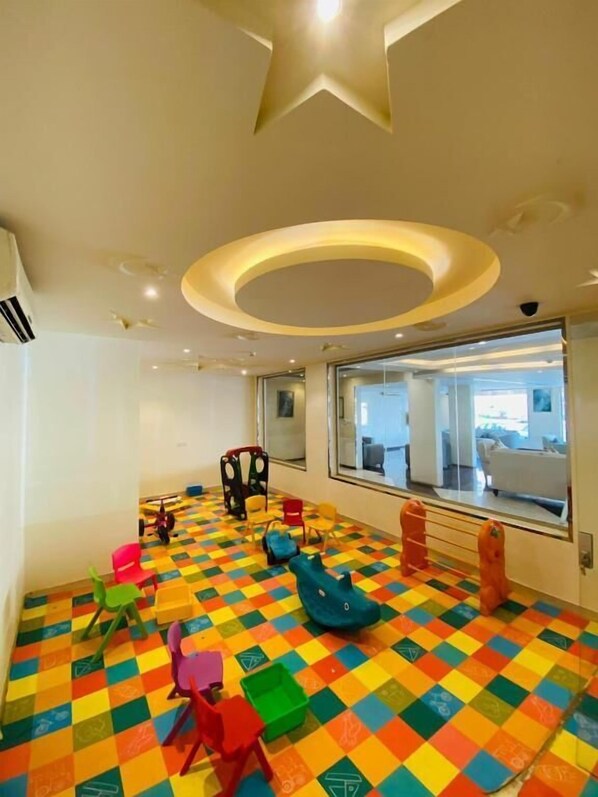A brightly colored playroom with a star-shaped ceiling design and a large window offering a view of the outside.