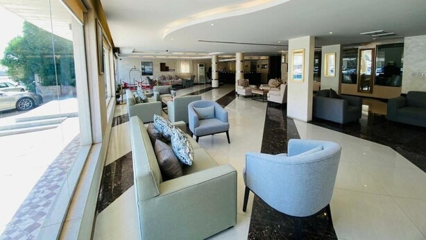 A modern hotel lobby with a curved ceiling, seating areas, and a reception desk. - Towlan Khress Serviced Apartments (Riyadh)