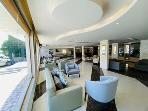 Un moderno vestíbulo de hotel con techo curvo, zonas de estar y una recepción.