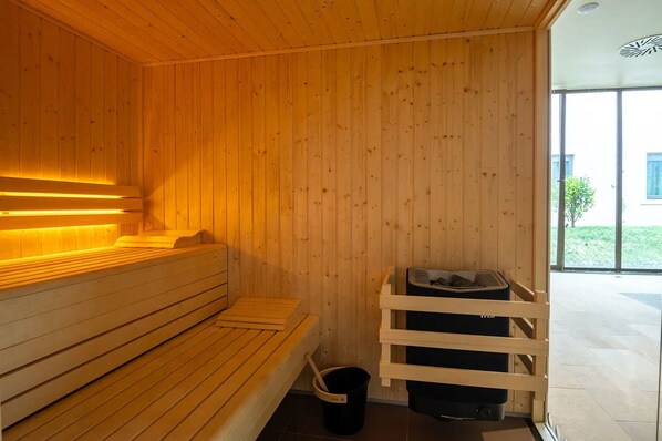 A wooden sauna with benches and a bench seat, a wooden bench, a sauna heater, and a sauna bench.