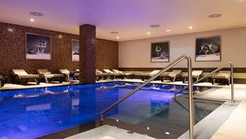A swimming pool with lounge chairs, a central pillar, and framed pictures on the walls.