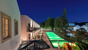 A modern building with a swimming pool, outdoor seating, and a staircase leading to a balcony. - Vila Gale Collection Tomar Hotel (Tomar)