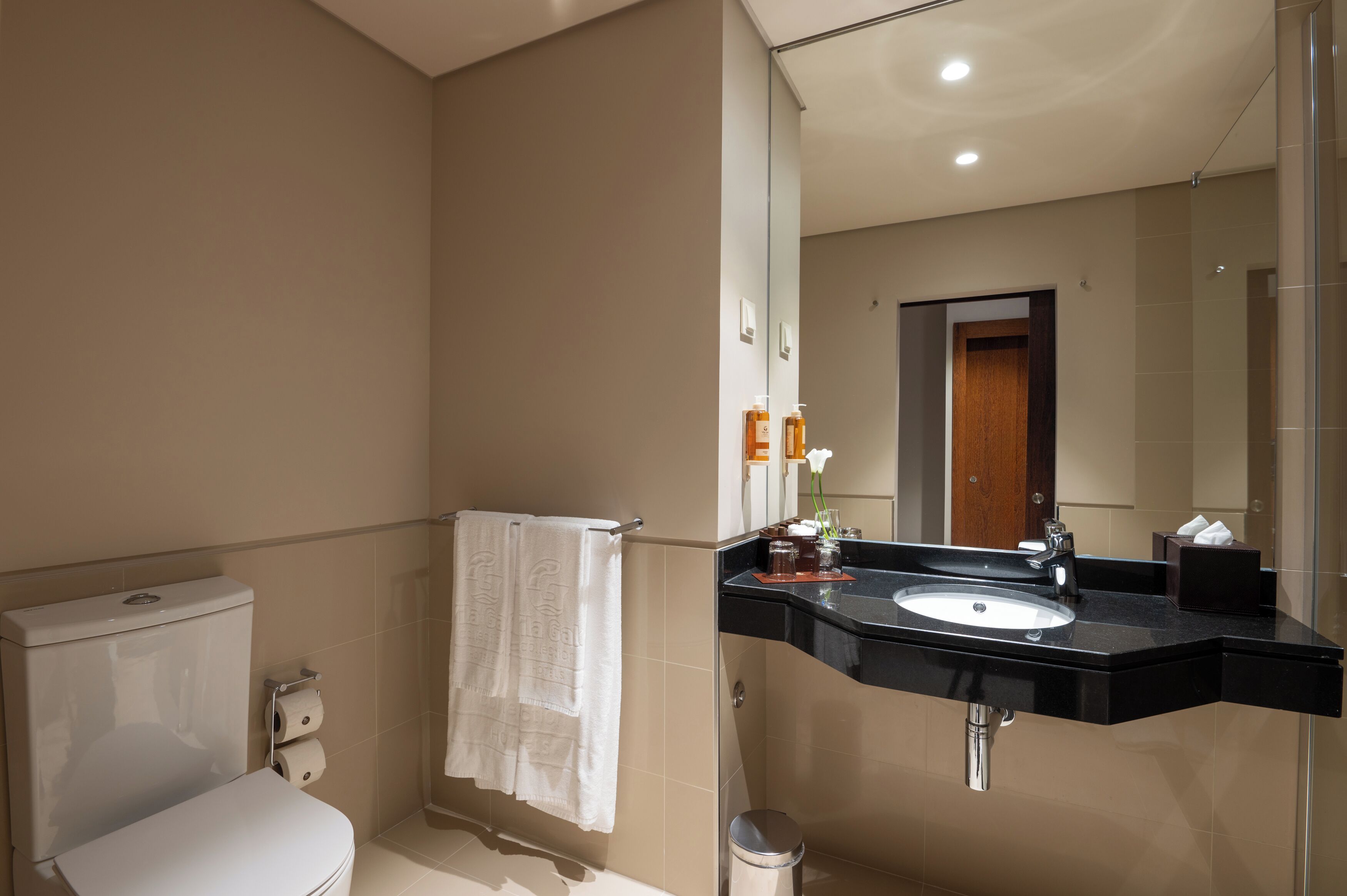 A modern bathroom with a toilet, sink, and mirror.