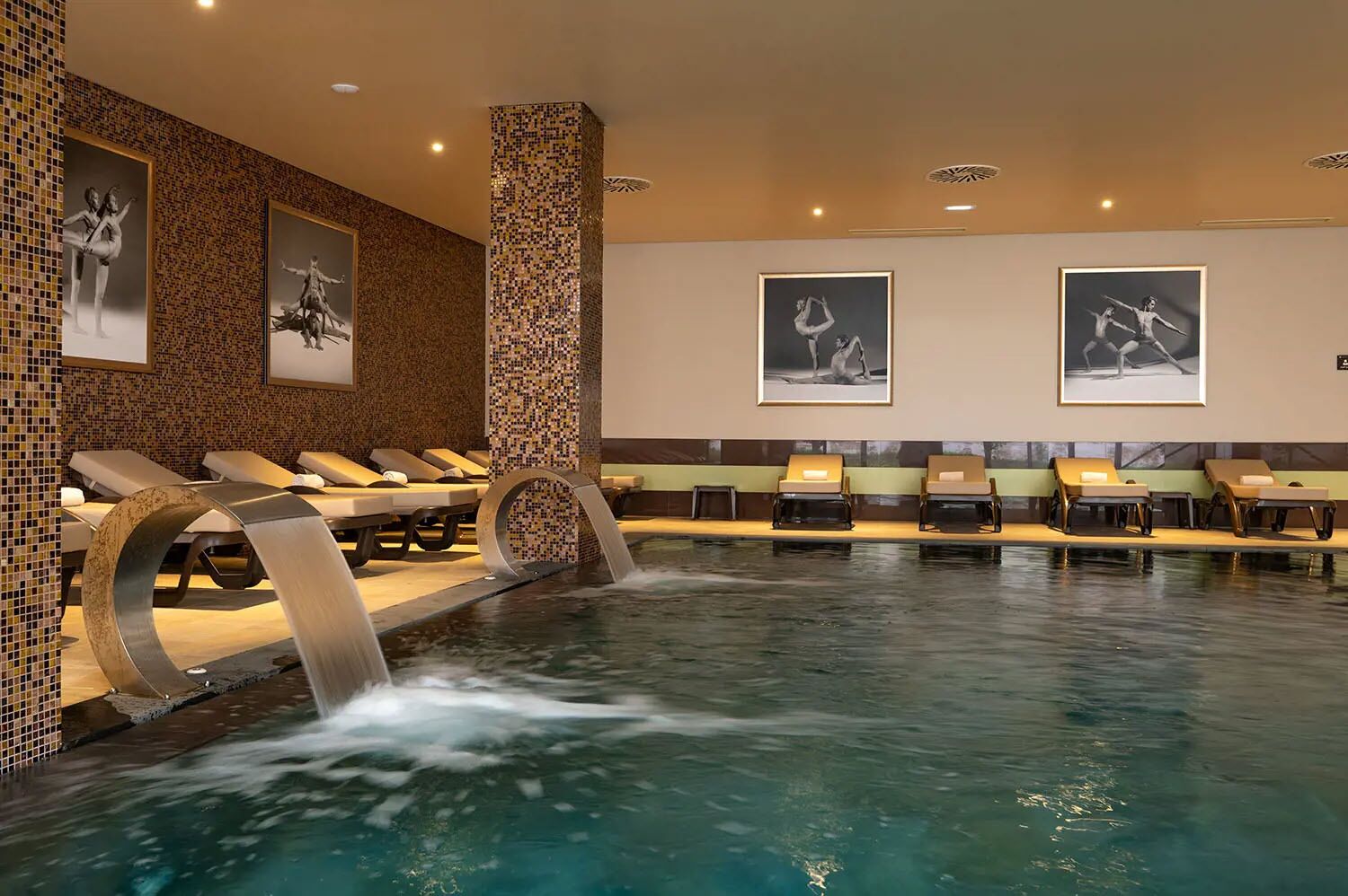 A spa area with a pool, lounge chairs, and framed artwork on the walls.