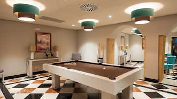 A pool table in a room with a checkered floor, recessed lighting, and a framed picture on the wall.