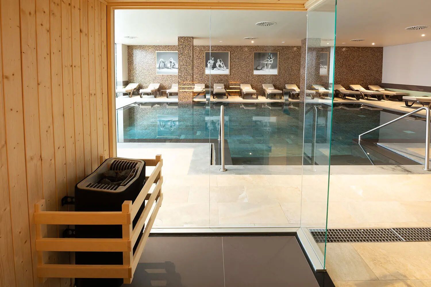 Un área de piscina interior moderna con sillones reclinables y una sauna.