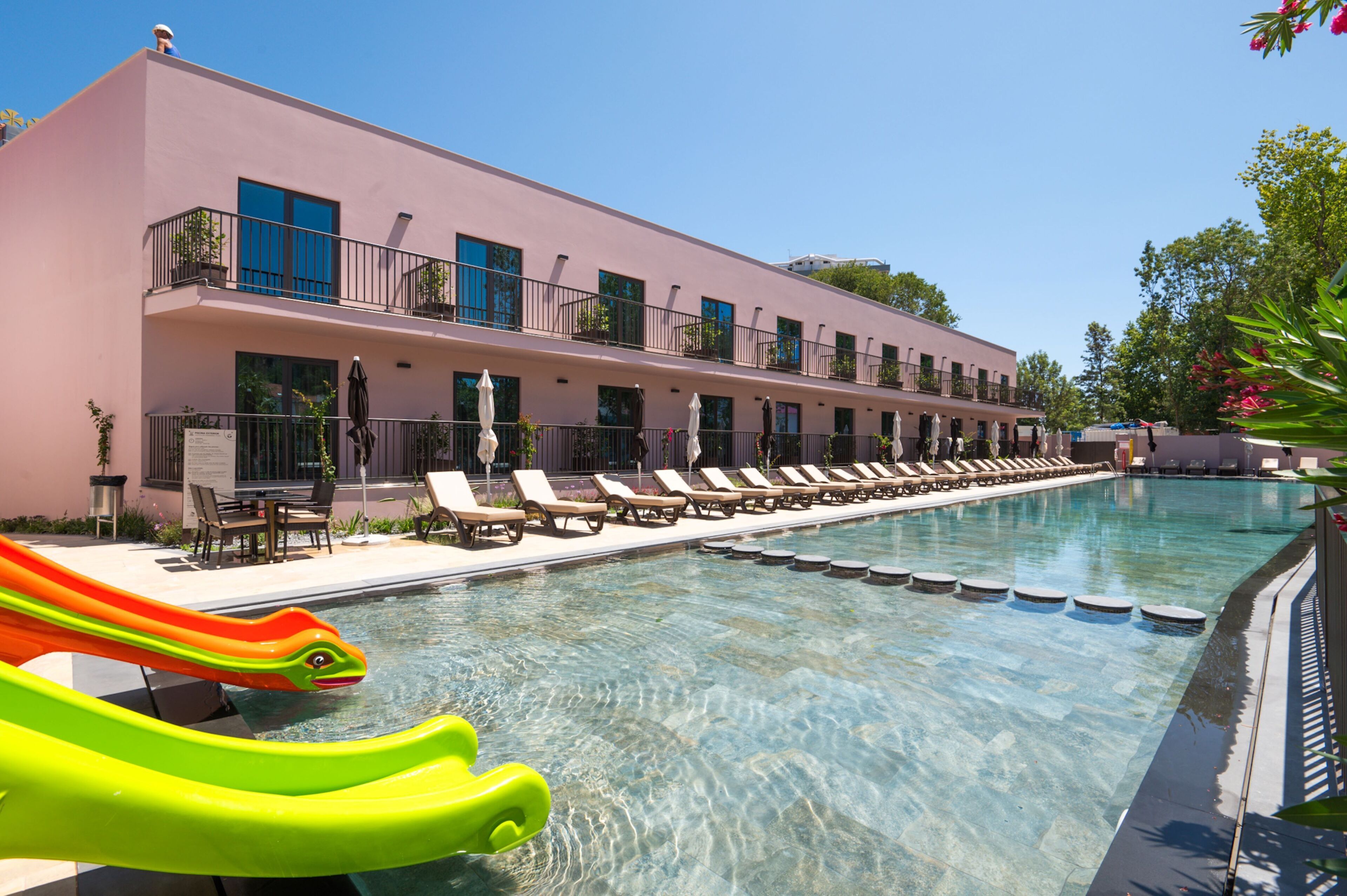 Un hotel con piscina, tumbonas y un tobogán.