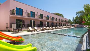 Un hotel con piscina, tumbonas y un tobogán.