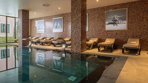 A modern indoor pool area with lounge chairs and framed artwork on the walls. - Vila Gale Collection Tomar Hotel (Tomar)