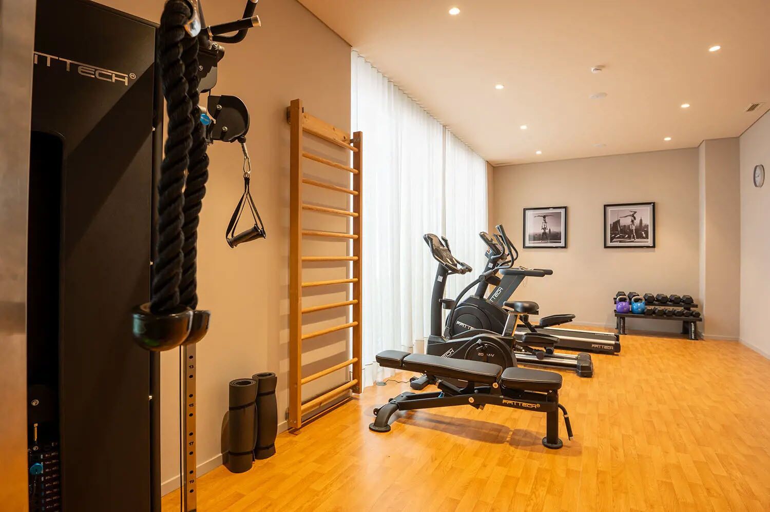 Een sportschool met cardioapparatuur, een optrekstang en een dumbbellrek.