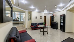 Ein modernes Wohnzimmer mit einem schwarz-roten Sofa, einem runden Tisch und einer Treppe, die zu einer oberen Etage führt.