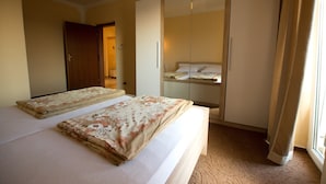 A hotel room with two beds, a wardrobe, and a large window with curtains.