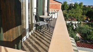A balcony with a table and chairs, overlooking a residential area with houses and trees.