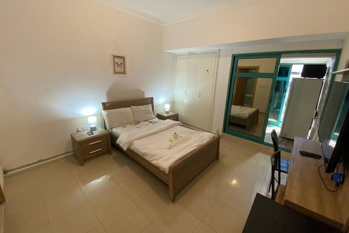 A bedroom with a bed, bedside tables, a wardrobe, and a desk with a chair.