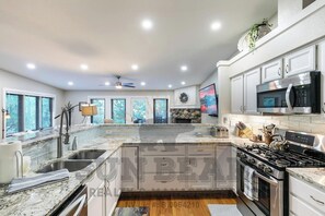 A modern kitchen with granite countertops, stainless steel appliances, and a large island. - Cozy and Modern Condo w a Summer Pool! (TC10) (Incline Village)