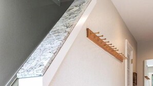 Een trap met een marmerachtige afwerking, een houten wandrek en een witte deur met ventilatie.