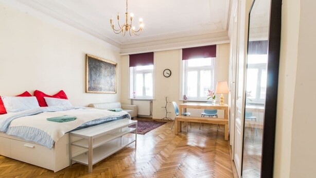 A bedroom with a bed, bedside table, and a desk with a chair.